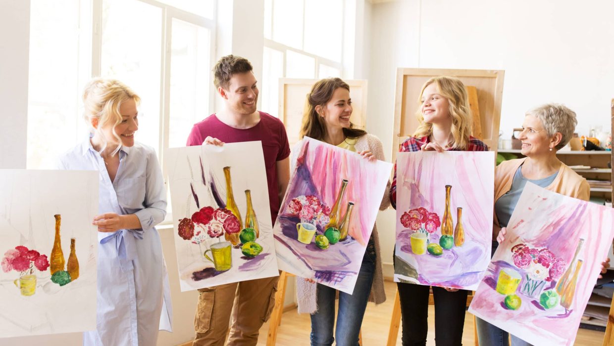 painting, education and people concept - group of artists or students holding still life pictures at art school studio